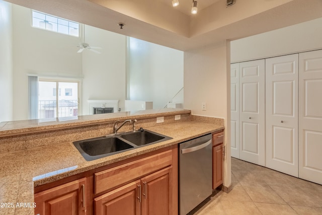 kitchen with a sink, a fireplace, light countertops, dishwasher, and light tile patterned floors