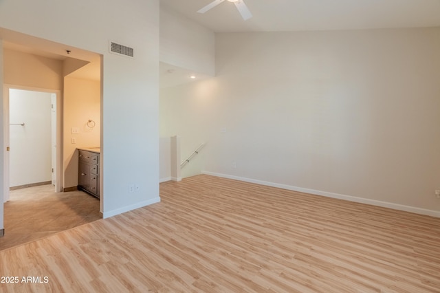 spare room with ceiling fan, high vaulted ceiling, baseboards, light wood-type flooring, and visible vents