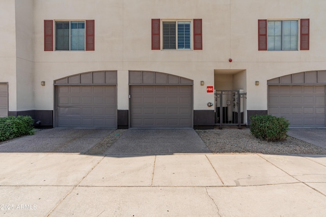 view of property with a garage, driveway, and stucco siding