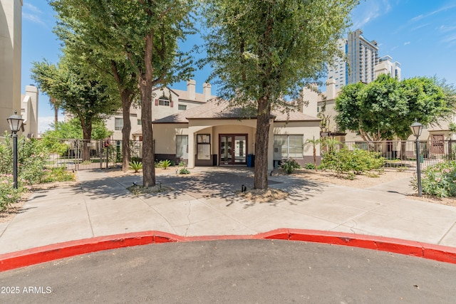 view of front of home with fence, french doors, a gate, and stucco siding