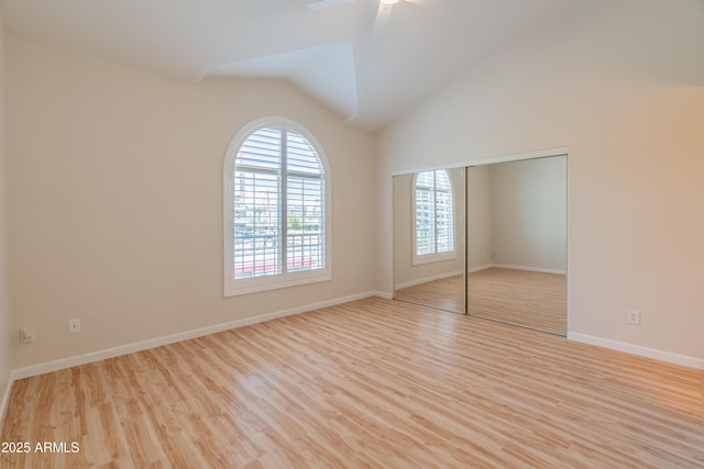 unfurnished bedroom with a closet, lofted ceiling, wood finished floors, and multiple windows
