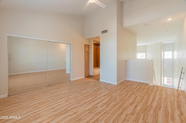 unfurnished bedroom featuring connected bathroom, baseboards, light wood-type flooring, visible vents, and a closet