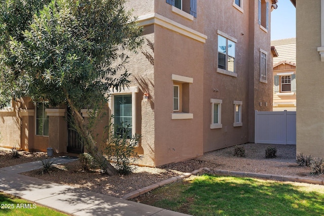 view of side of property featuring fence and stucco siding