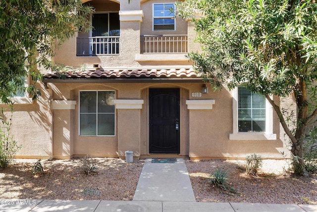 view of exterior entry with a tile roof and stucco siding