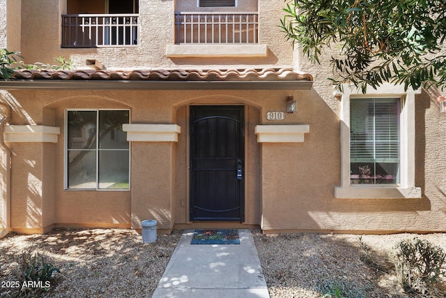 view of exterior entry with a tile roof and stucco siding