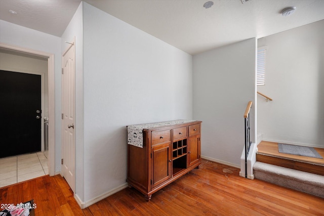 interior space featuring stairs, light wood-style flooring, and baseboards