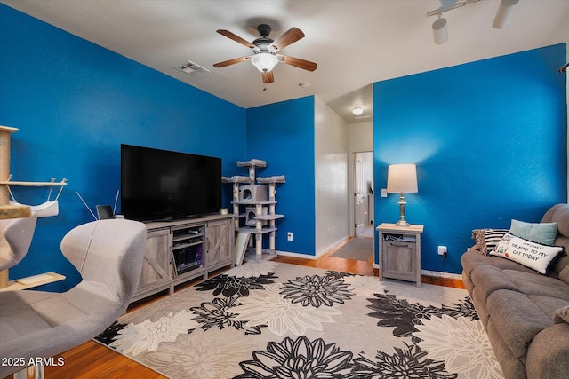 living room with visible vents, ceiling fan, light wood-style flooring, and baseboards