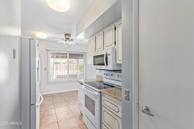 kitchen featuring light tile patterned flooring, white appliances, ceiling fan, and light stone countertops