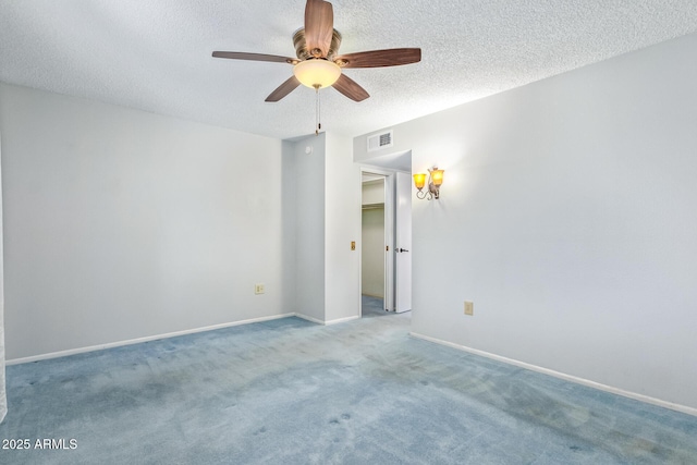 carpeted spare room featuring ceiling fan and a textured ceiling