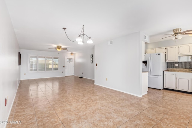 unfurnished living room featuring light tile patterned flooring and ceiling fan with notable chandelier