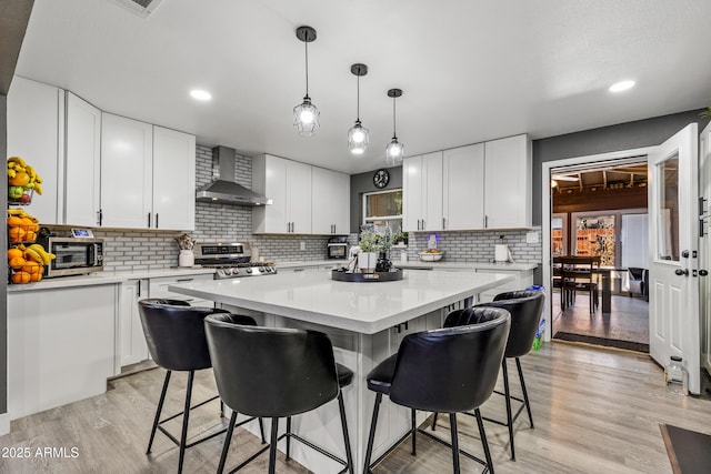 3207 N Steves Blvd, Flagstaff, AZ 86004 - kitchen featuring a breakfast bar, light wood-style floors, appliances with stainless steel finishes, a center island, and wall chimney exhaust hood