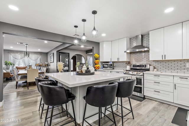 3207 N Steves Blvd, Flagstaff, AZ 86004 - kitchen with appliances with stainless steel finishes, a kitchen breakfast bar, a center island, and wall chimney exhaust hood