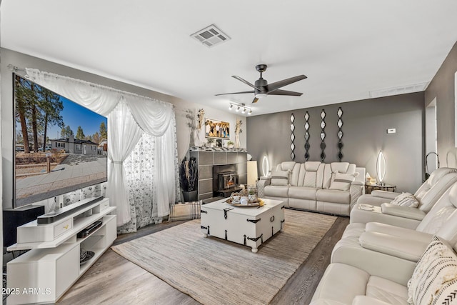 3207 N Steves Blvd, Flagstaff, AZ 86004 - living room with a tile fireplace, wood finished floors, visible vents, and a ceiling fan