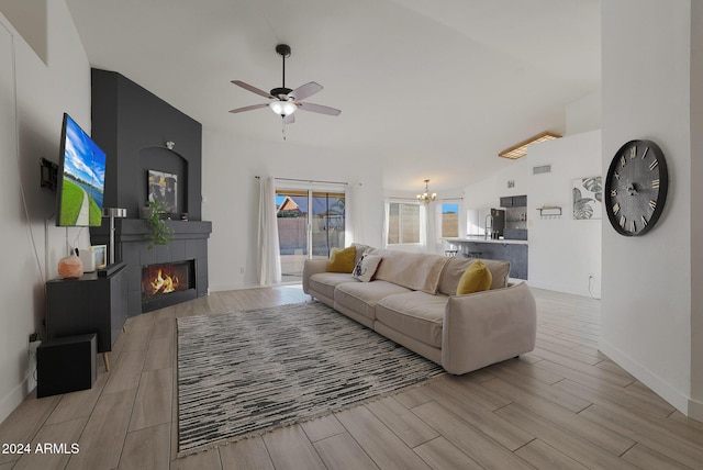 living room with lofted ceiling, ceiling fan with notable chandelier, and a fireplace