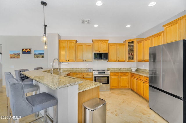 kitchen featuring visible vents, a peninsula, appliances with stainless steel finishes, glass insert cabinets, and a kitchen breakfast bar