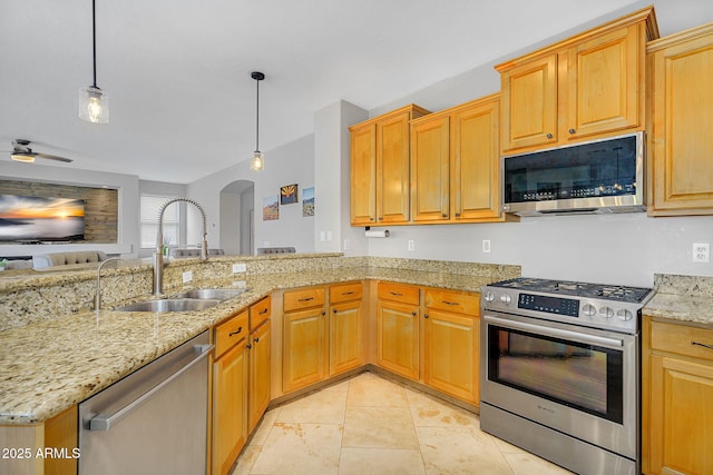 kitchen featuring light stone countertops, appliances with stainless steel finishes, arched walkways, a sink, and pendant lighting