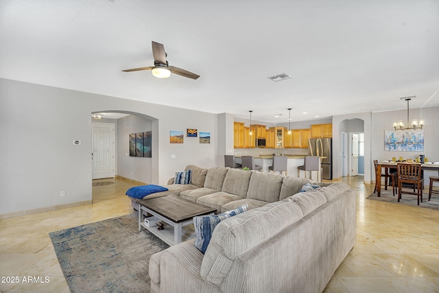 living room with arched walkways, visible vents, baseboards, and ceiling fan with notable chandelier