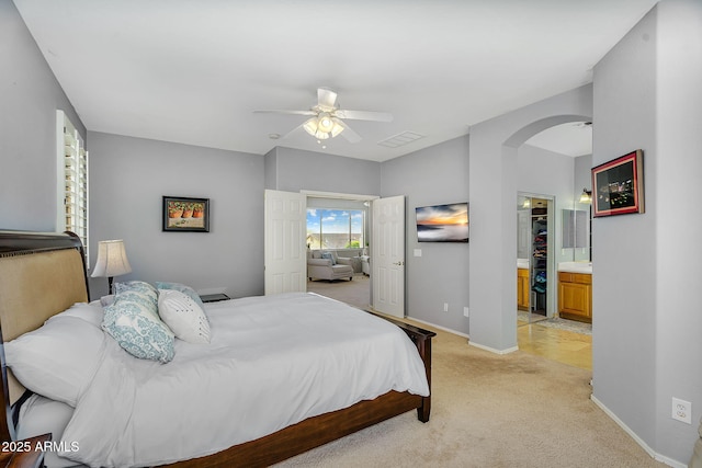 bedroom with light colored carpet, baseboards, arched walkways, visible vents, and a ceiling fan