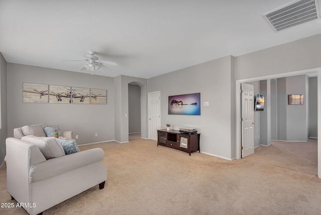 living area featuring carpet floors, baseboards, visible vents, arched walkways, and ceiling fan