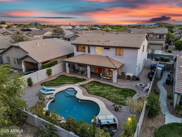 back of house featuring a fenced backyard, an outdoor living space with a fire pit, a residential view, and a patio