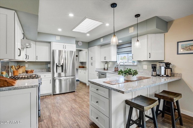 2846 E Lupine Ave, Phoenix, AZ 85028 - kitchen featuring a peninsula, light wood-style floors, a sink, appliances with stainless steel finishes, and a skylight