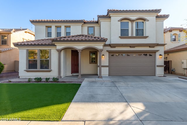 mediterranean / spanish-style home featuring a front yard and a garage