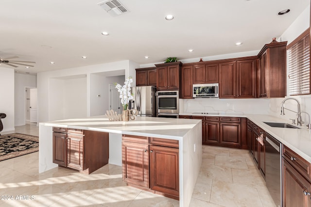 kitchen featuring appliances with stainless steel finishes, a center island, ceiling fan, and sink