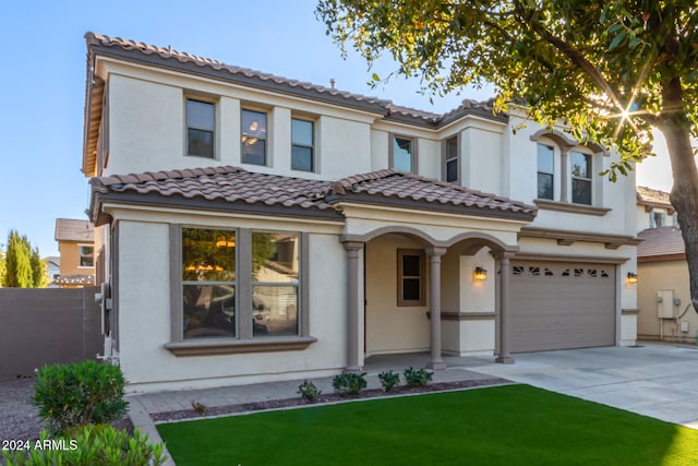 mediterranean / spanish home featuring a front lawn and a garage