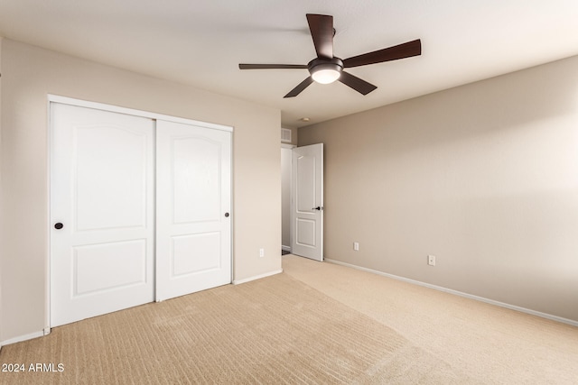 unfurnished bedroom with ceiling fan, a closet, and light colored carpet