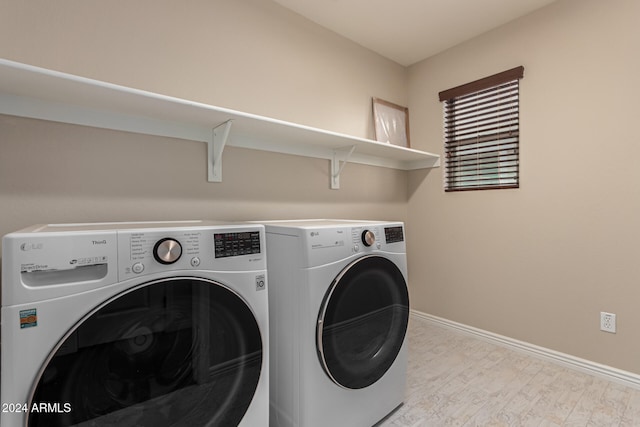 laundry area with washing machine and clothes dryer and light hardwood / wood-style floors