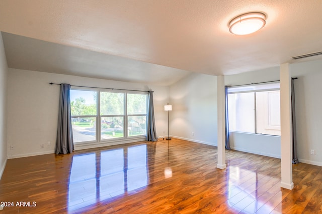 unfurnished room with a textured ceiling and dark hardwood / wood-style floors