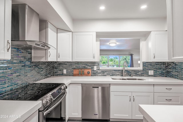 kitchen featuring stainless steel appliances, white cabinetry, and wall chimney exhaust hood