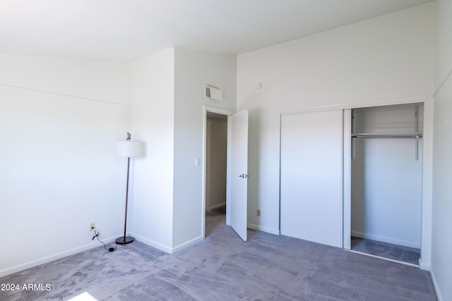 unfurnished bedroom featuring carpet, high vaulted ceiling, and a closet