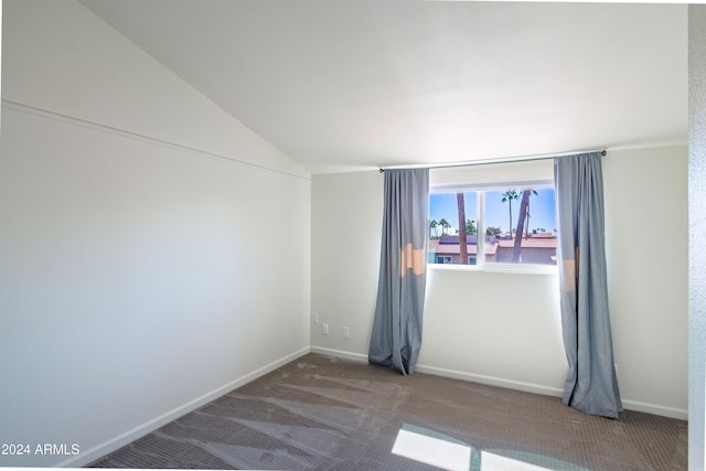 empty room featuring carpet and vaulted ceiling