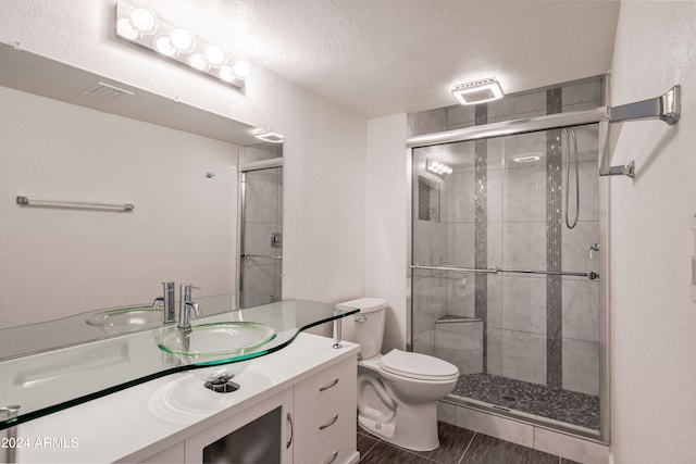 bathroom featuring toilet, vanity, a textured ceiling, and walk in shower