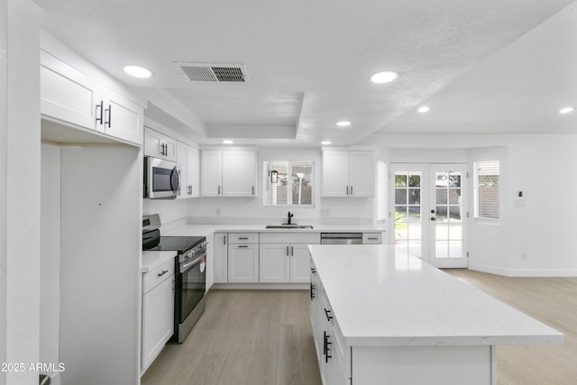 kitchen featuring appliances with stainless steel finishes, a kitchen island, and white cabinets