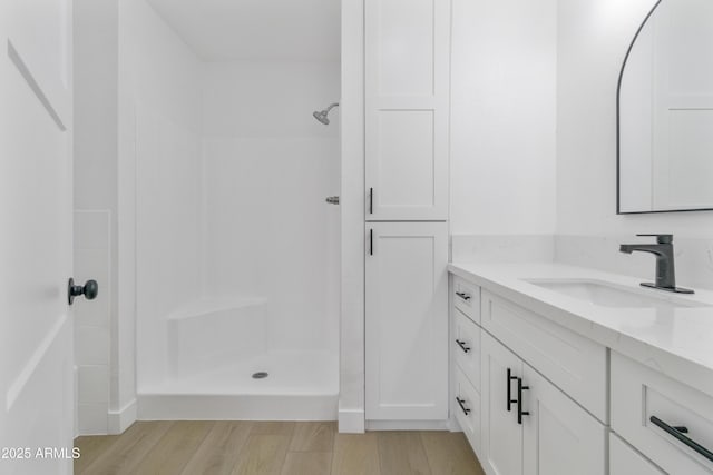 bathroom featuring vanity, wood-type flooring, and a shower