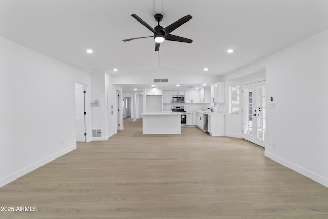 unfurnished living room featuring vaulted ceiling, ceiling fan, light hardwood / wood-style floors, and french doors