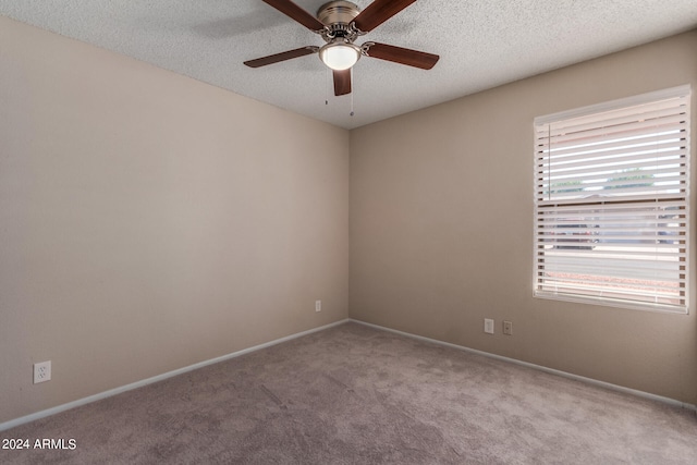 spare room with a textured ceiling, ceiling fan, and light colored carpet