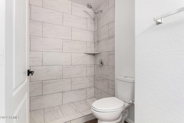 bathroom with toilet and tiled shower