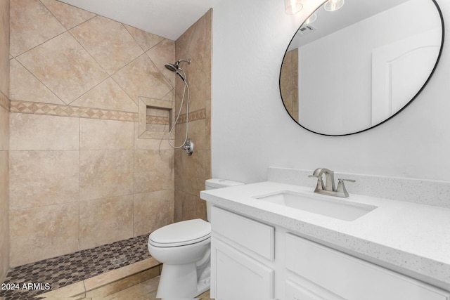 bathroom featuring tile patterned floors, vanity, toilet, and tiled shower