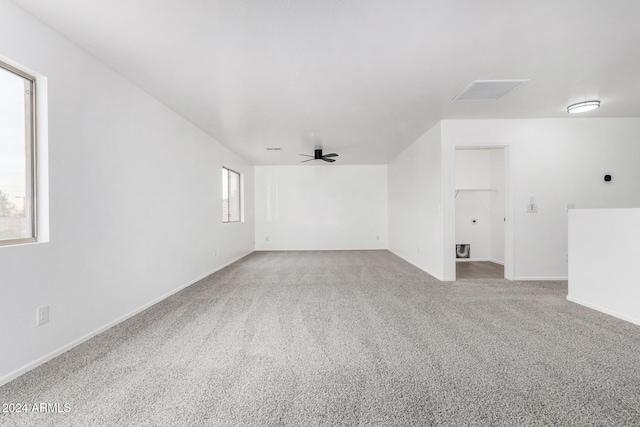 carpeted spare room featuring ceiling fan and a wealth of natural light