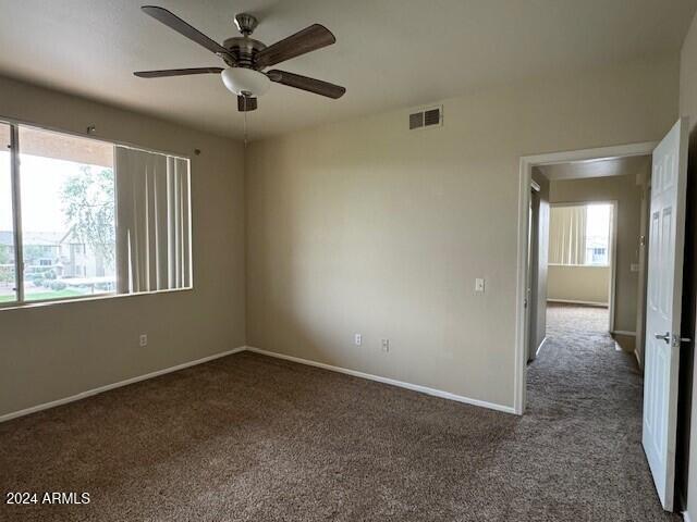 carpeted empty room with a wealth of natural light and ceiling fan