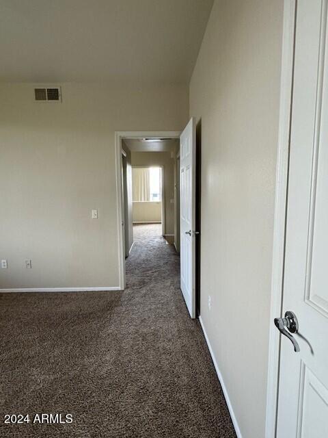 corridor featuring dark colored carpet