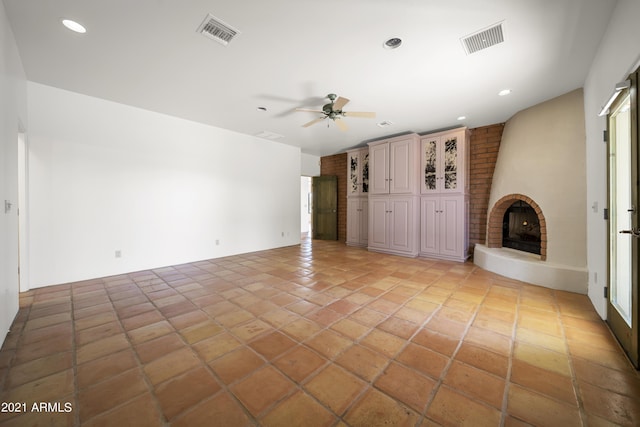 unfurnished living room with a brick fireplace and ceiling fan