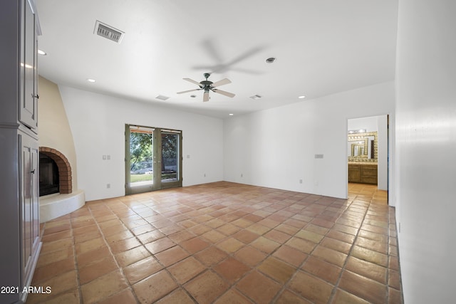 unfurnished living room featuring ceiling fan and a brick fireplace