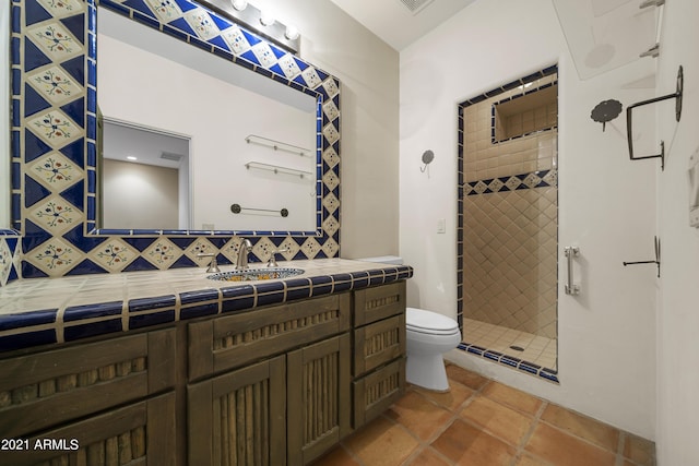 bathroom with tiled shower, vanity, toilet, and tile patterned flooring