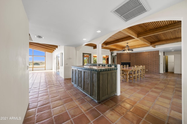 kitchen with vaulted ceiling with beams, hanging light fixtures, tile patterned flooring, wooden ceiling, and an inviting chandelier