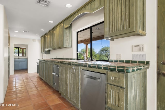 kitchen featuring light tile patterned floors, sink, dishwasher, tile counters, and green cabinetry