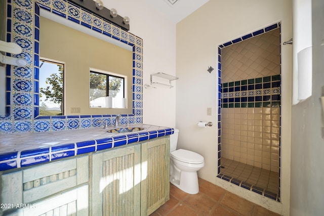 bathroom with tile patterned flooring, tiled shower, vanity, decorative backsplash, and toilet